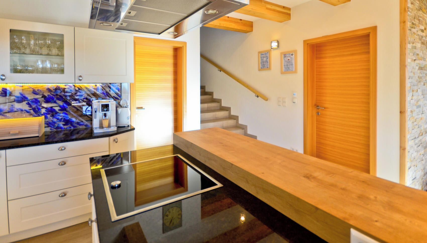 Eine moderne Küche mit einer Holz Arbeitsplatte, weißen Schränken und einer Glasrückwand.