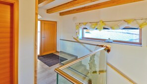 A staircase with glass railings and a wooden door at the top.
