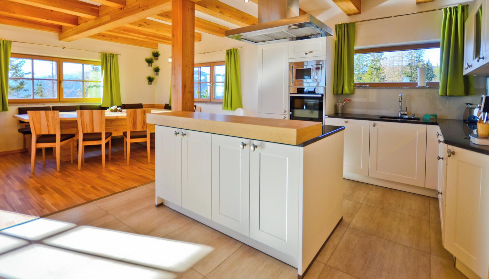 A modern kitchen with white cabinets, a wooden island, and a dining area with a wooden table and chairs.