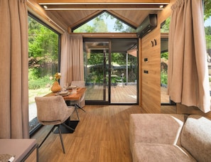 Ein modernes Interieur mit Essbereich, einer Couch und Blick ins Freie.