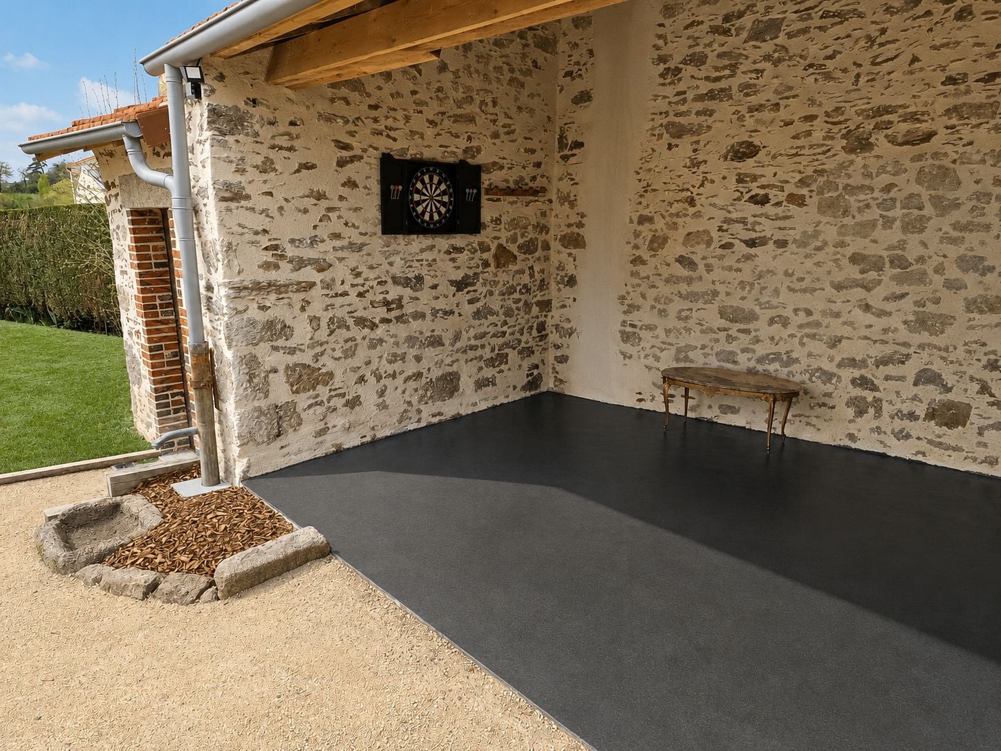 Une pièce avec un mur en pierre, un jeu de fléchettes et une petite table.