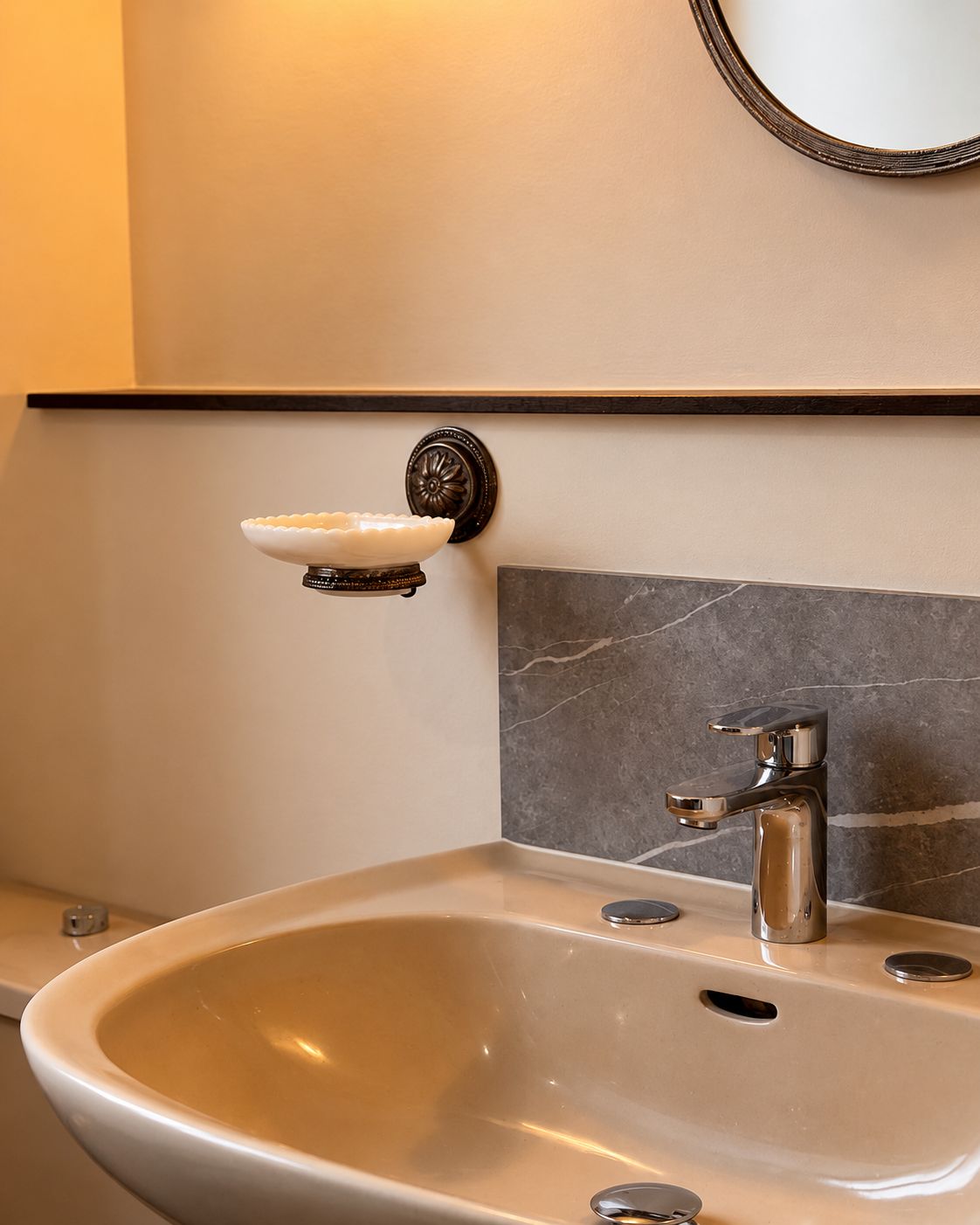 A bathroom with a white sink, a single faucet, and a wall-mounted soap dish.