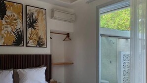 Un dormitori amb un llit, un panell de capçal de fusta, aire condicionat fixat a la paret i vista a un balcó.