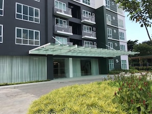 A modern building with multiple balconies, a covered entrance, and a landscaped garden area. - Studio Unit at Abreeza Place (Davao)
