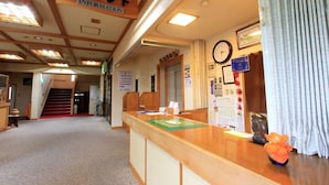 A reception area with a wooden reception desk, a clock, and a bulletin board with various notices. - Yanaginoyu Hotel (Aomori)