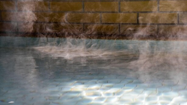 A pool with a brick wall in the background. - Yanaginoyu Hotel (Aomori)