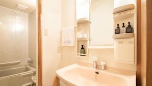 A bathroom with a bathtub, a sink, a mirror, and a shelf with toiletries. - Yanaginoyu Hotel (Aomori)
