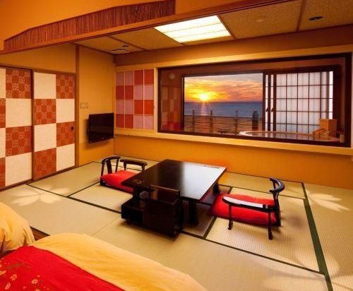Una habitación japonesa tradicional con suelo de tatami, una mesa baja con sillas, una cama y vistas a la puesta de sol a través de una ventana.