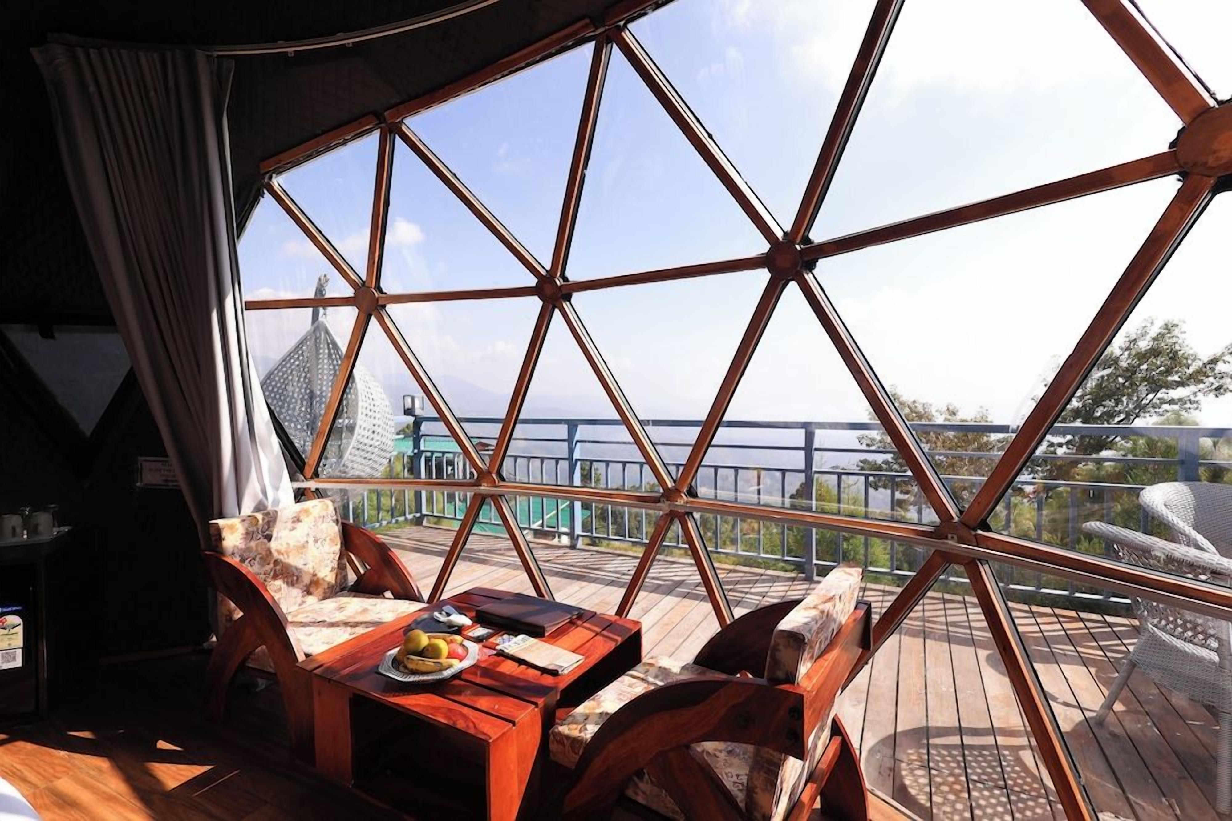 A room with a large window, wooden furniture, and a view of a distant building.