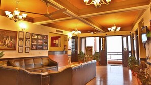 A reception area with a leather sofa, chandeliers, framed certificates, and a reception desk. - Ecko Kasang Regency (Lansdowne)