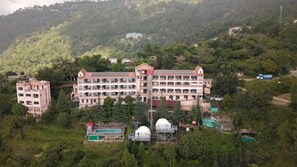 A multi-story hotel with a central courtyard, surrounded by lush greenery and hills. - Ecko Kasang Regency (Lansdowne)