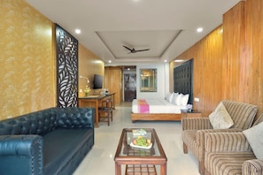 Habitación de hotel con sofá, cama, zona de comedor y televisor.
