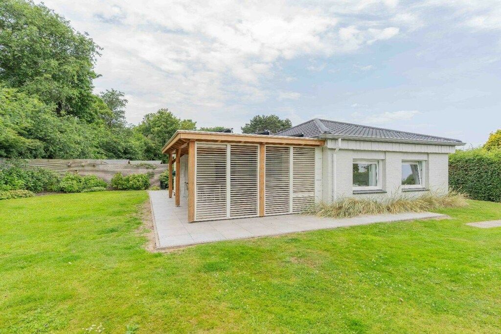 A modern house with a covered patio, a small garden, and a paved driveway.