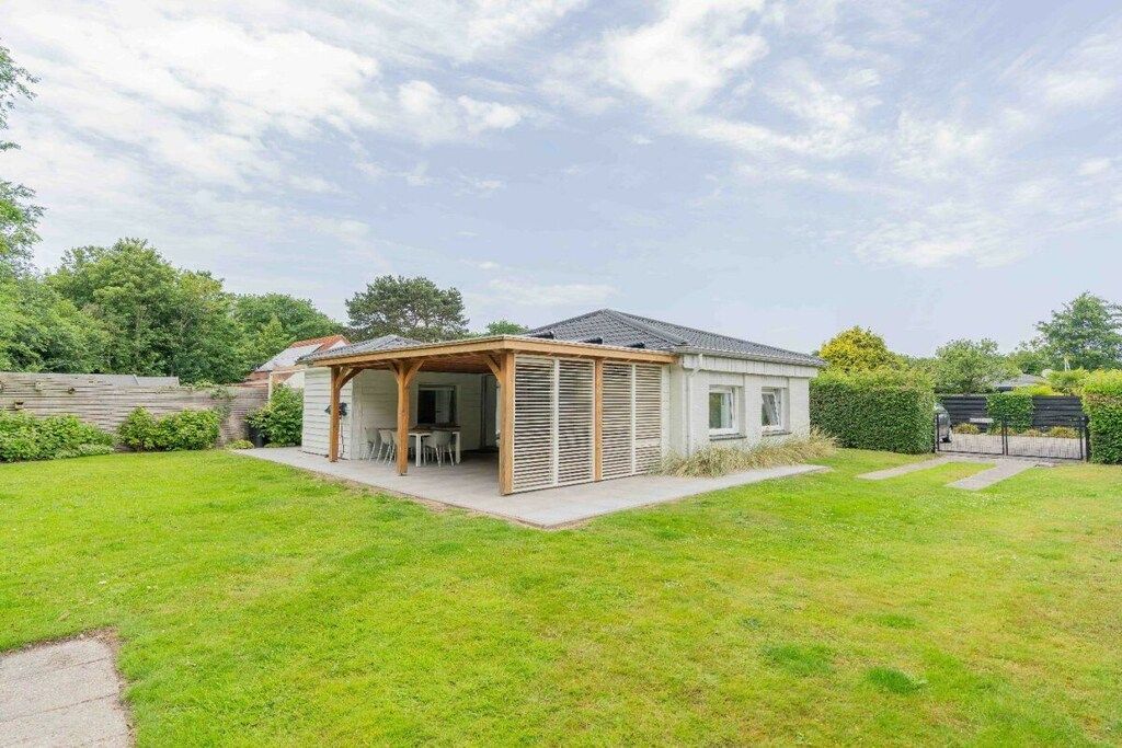 A single-story house with a covered patio area, a small garden, and a wooden fence.