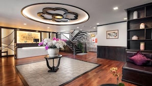 A hotel lobby with a reception desk, a staircase, and a seating area. - Peony Cruises (Hai Phong)