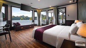 A modern hotel room with a large bed, a desk, and a view of the water. - Peony Cruises (Hai Phong)