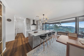 A modern kitchen with a large island, bar stools, and a view of the outdoors. - Fletchers Ridge Entire Estate (Montville)