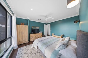 Een slaapkamer met een bed, een kledingkast, een televisietoestel en een plafondventilator.