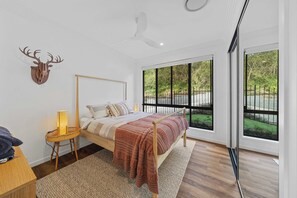 A bedroom with a bed, a wall-mounted deer head, a window with a view of greenery, and a ceiling fan. - Fletchers Ridge Entire Estate (Montville)