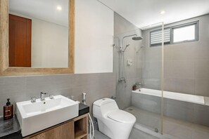 A modern bathroom with a double sink, toilet, and a glass-enclosed shower area.