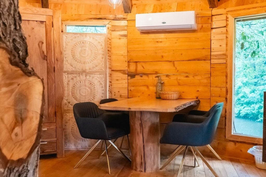 Puisesti sisustettu tila, jossa on ruokapöytä, tuoleja ja ilmastointilaite.