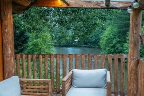 Une terrasse en bois avec un banc et une vue sur une rivière bordée d’une végétation luxuriante.