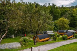 A row of rustic wooden cabins with sloped roofs, surrounded by lush greenery and trees.
