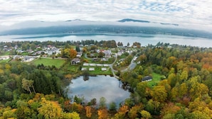 A lakeside residential area with houses, a pond, and a view of a lake and mountains.