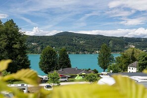 A lakeside view with RVs parked, a clear sky, and a forested hill in the background.