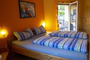 A single bed with striped bedding, a nightstand, a wall-mounted lamp, and a painting. - Holiday home with 1 bedroom (St. Aldegund)