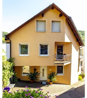 A two-story building with a balcony on the upper floor. - Holiday home with 1 bedroom (St. Aldegund)