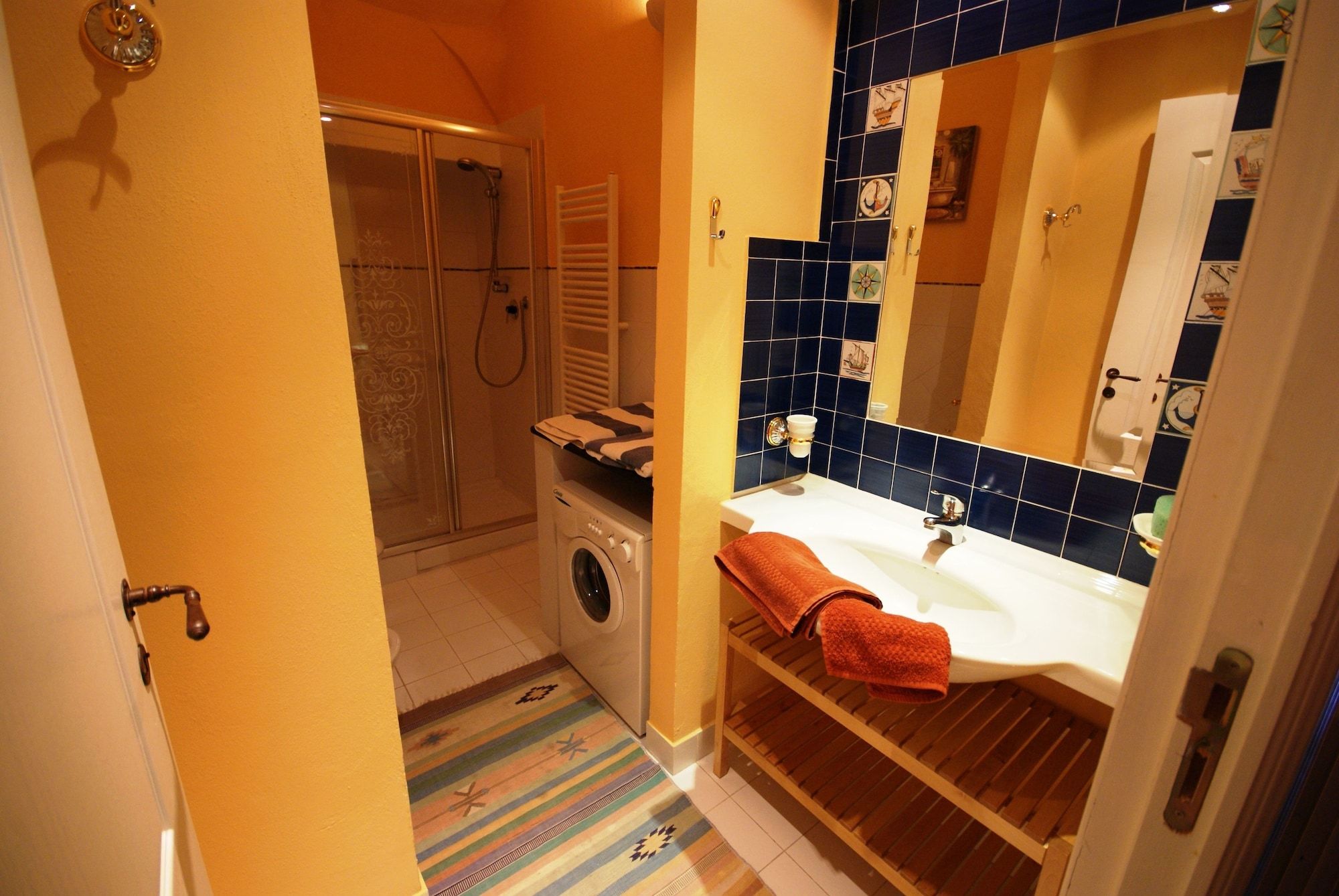 Un bagno compatto con doccia, lavatrice e lavandino con porta asciugamani.