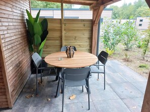 Eine Terrasse im Freien mit einem runden Holztisch, vier Stühlen und einer dekorativen Vase.