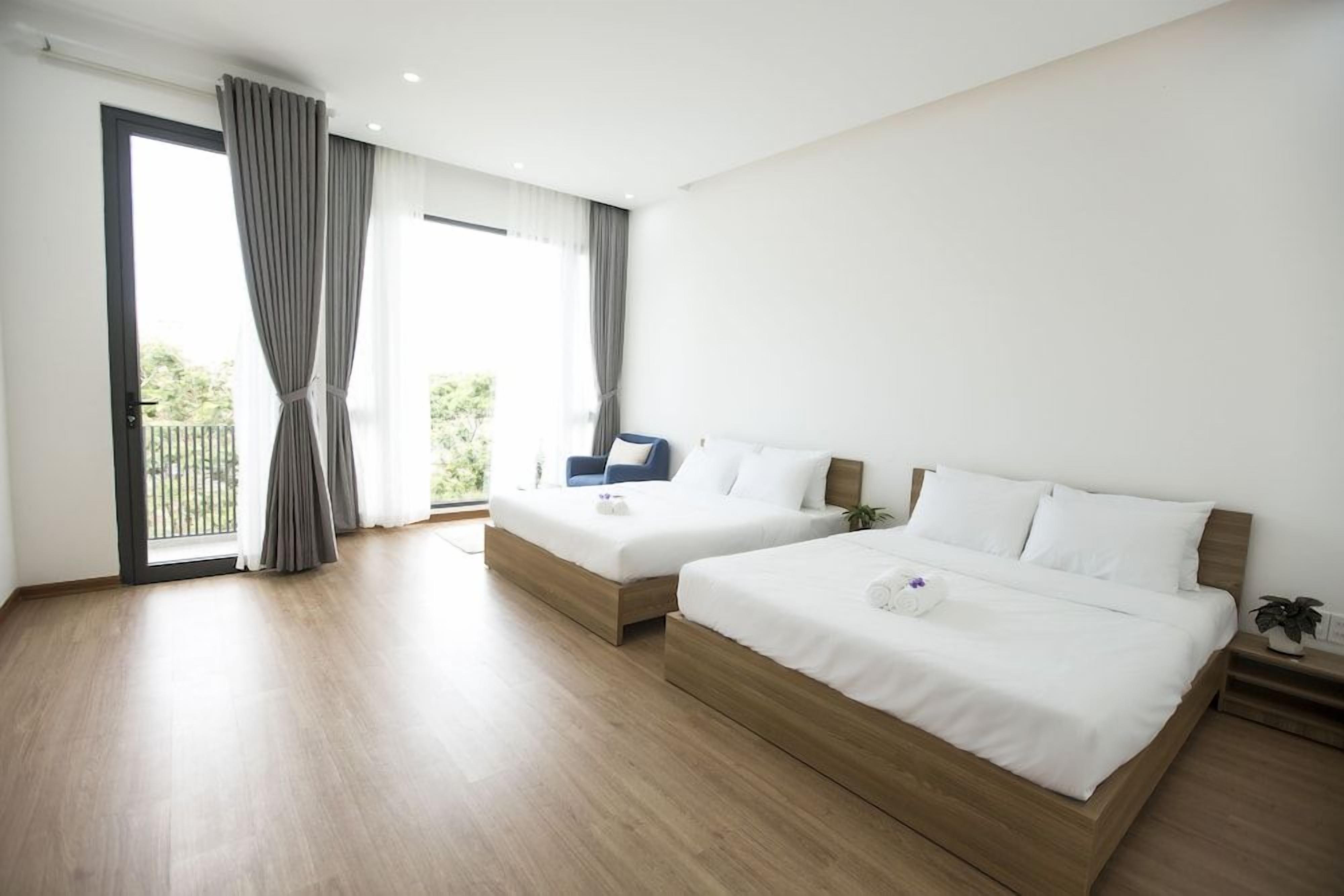 A hotel room with two beds, a balcony, and a large window.
