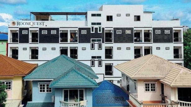 A multi-story hotel with a modern design, featuring balconies and a prominent signage for 'ROOMQUEST.'