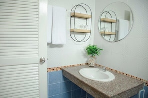 A bathroom with a white sink, two wall-mounted mirrors, a towel rack, and a small potted plant. - Roomquest Patong Phuket (Patong)