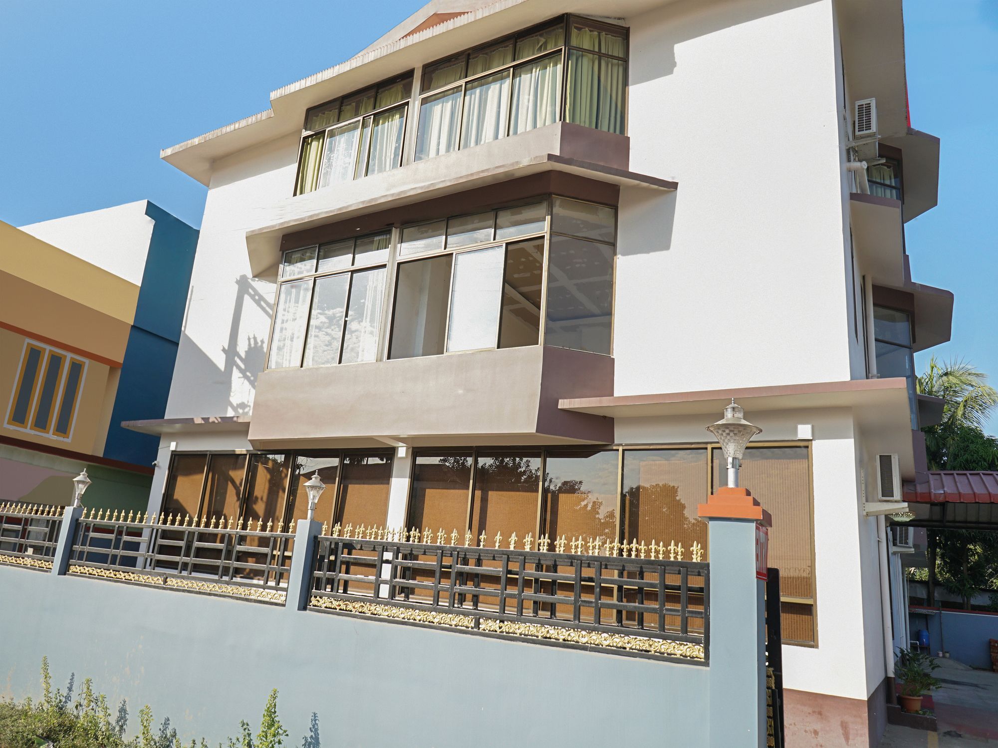 A multi-story residential building with a flat roof, large windows, and a decorative fence.