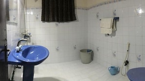 Een badkamer met een blauwe wastafel, een badkuip en een douchehoek.