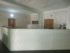 Zona de recepció amb un taulell de mosaiques de marbre, portes de fusta i un sostre amb un disseny decoratiu.