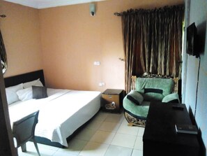 Una habitació d'hotel amb un llit, una cadira, una taula petita i una televisió.