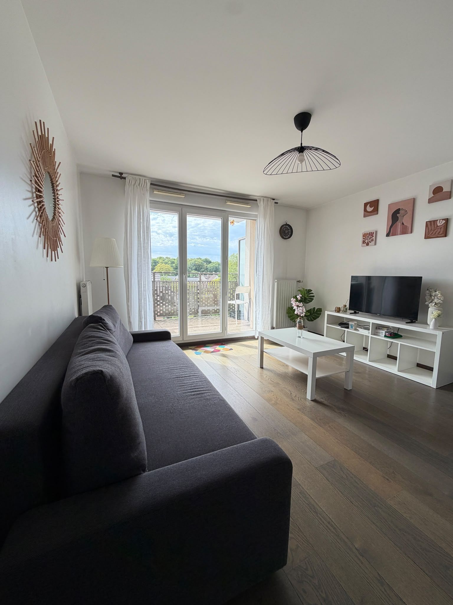 Een moderne woonkamer met een bank, een salontafel, een televisie en kunstwerken aan de muur.