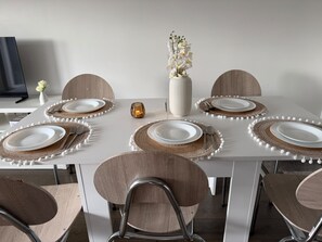 A dining table set with white plates, brown placemats, and a vase of white flowers. - L'Escale Parisienne: a perfect 2-bedroom apartment in charming Tremblay (Tremblay-en-France)