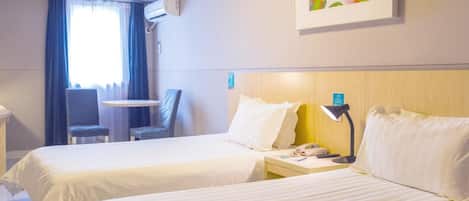 A hotel room with two beds, a desk, a chair, an air conditioning unit, and a painting on the wall.