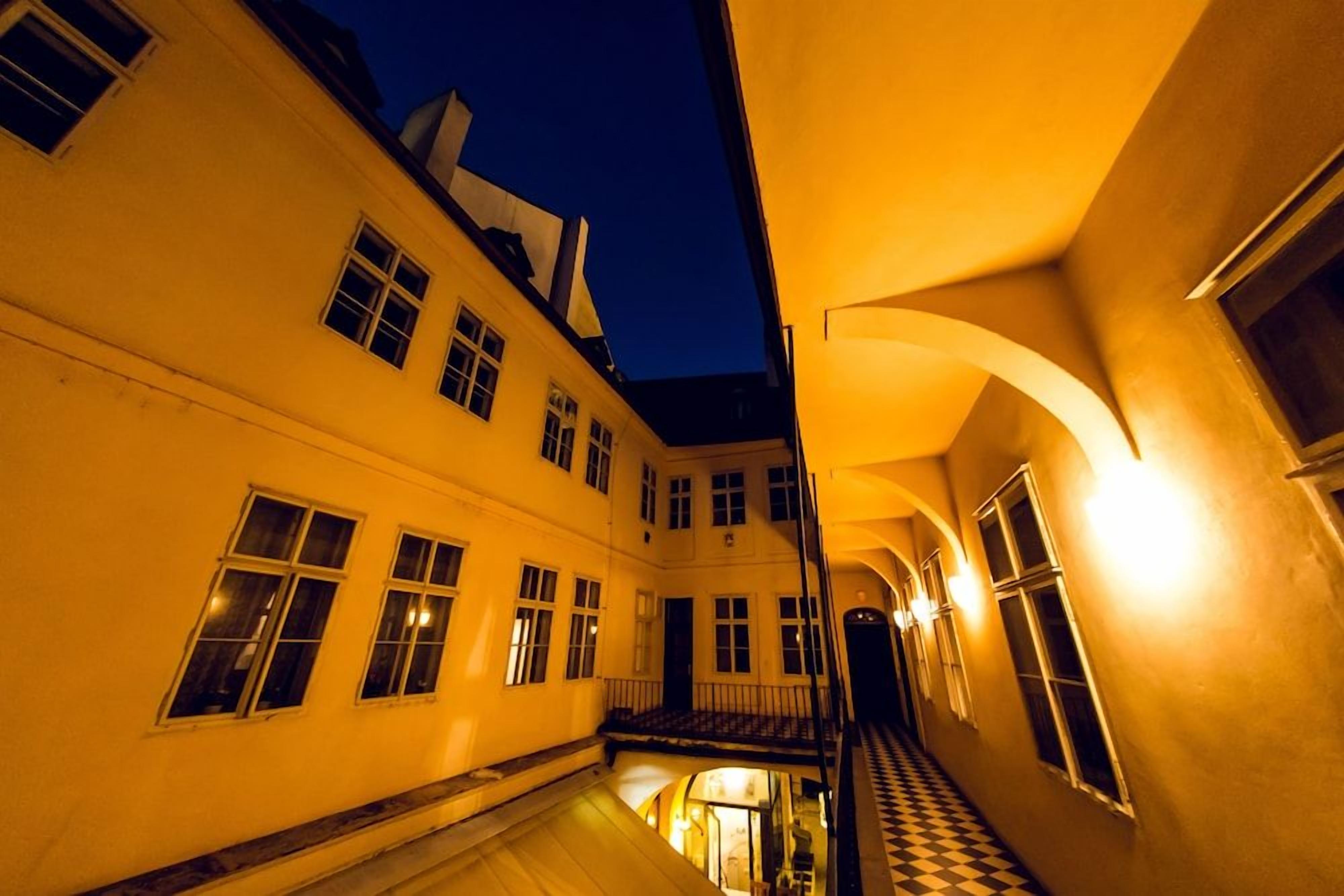 A corridor with a checkered floor, multiple windows, and a staircase leading to an upper level.