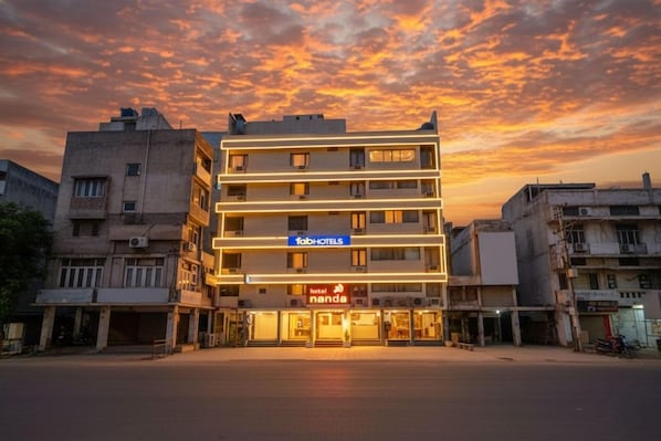 Un edificio de varios pisos con el letrero 'fabHOTELS', el letrero 'hotel nanda' y una vista despejada de la calle.