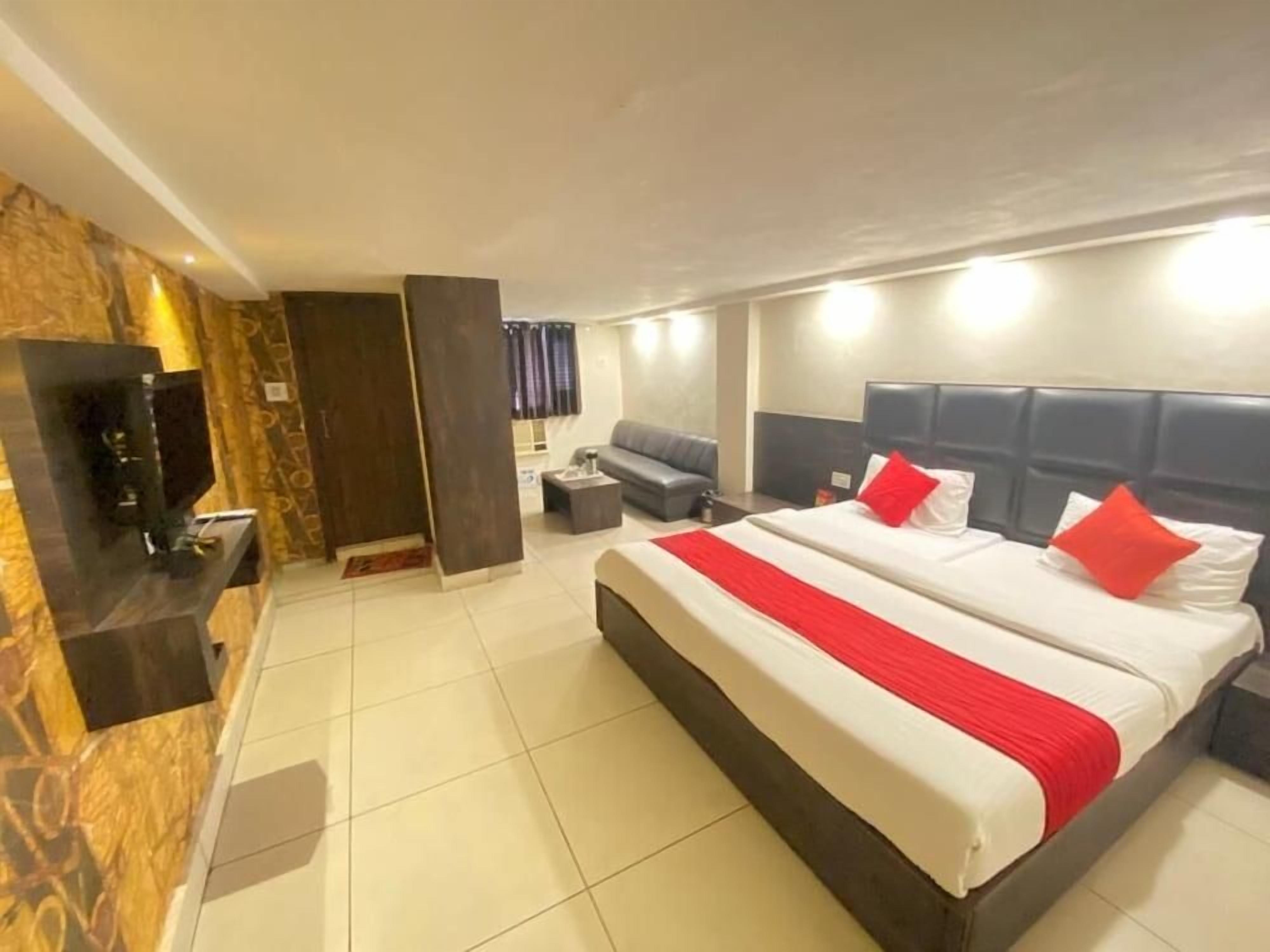 A hotel room with a large bed, a flat-screen TV, a sofa, and a small table.