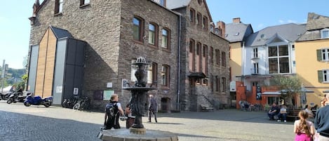 A stone building with a fountain in the center of a cobblestone square.