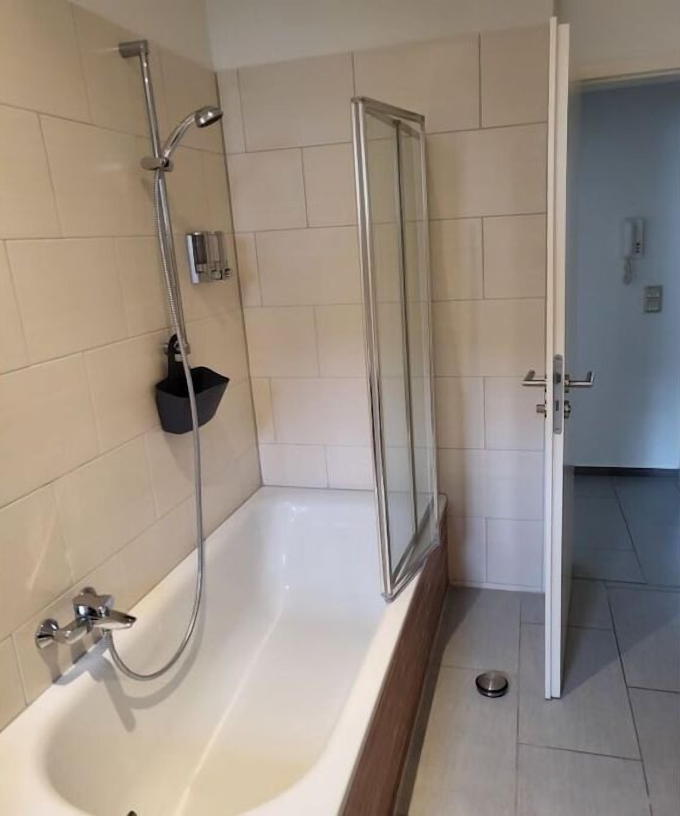 A bathroom with a bathtub, shower, and glass door.