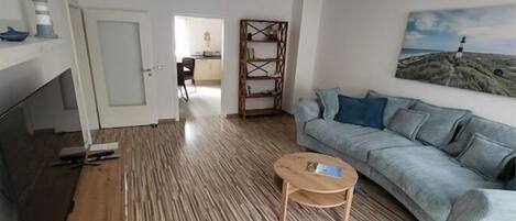 A modern living room with a wooden floor, a sofa, a coffee table, and a painting on the wall.