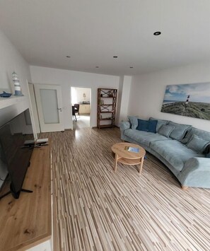A modern living room with a wooden floor, a sofa, a coffee table, and a painting on the wall. - Holiday apartment with 1 bedroom (Bernkastel-Kues)